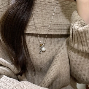 Tiger eye and pearl pendant necklace for women on brown knit sweater background