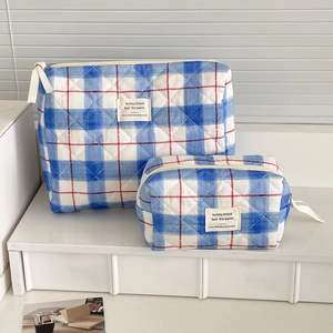 Close-up of blue checkerboard quilted makeup bags with red accents in two sizes