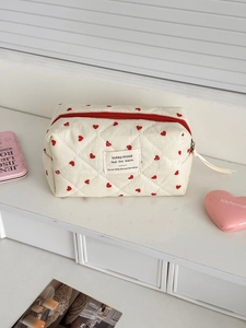Detailed macro of beige quilted makeup bag with red heart pattern and zip closure