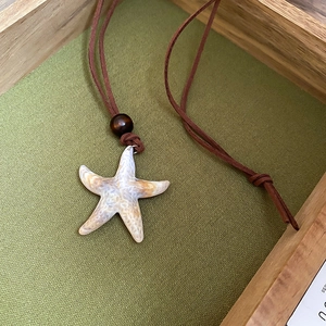 Detail of starfish pendant with wooden bead on brown leather cord necklace