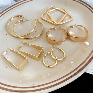 Detailed view of assorted gold geometric earrings arranged on a decorative ceramic tray