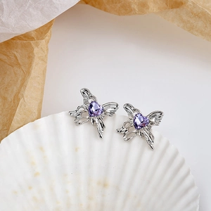Detail of silver butterfly stud earrings with purple heart crystals on shell