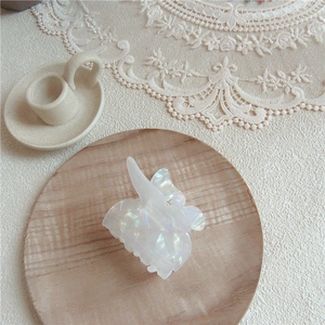 Detailed view of iridescent butterfly hair claw clip on a rustic wooden tray decoration