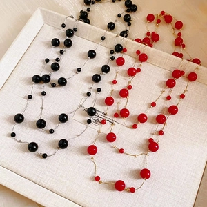Close-up of layered long pearl necklaces with black and red beads on jewelry display
