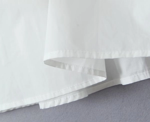 Detailed close-up of double-stitched hem on a white high-density cotton skirt