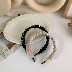 Dettaglio di cerchietti plissettati con perle beige e neri su vassoio in ceramica