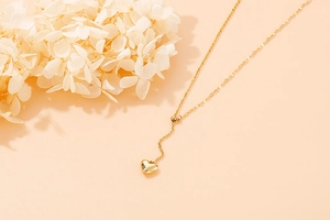 Macro detail of a minimalist gold heart pendant on a delicate chain necklace