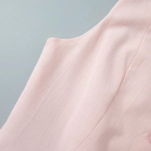 Gros plan sur la texture du lin rose et les coutures précises de la couture latérale du gilet