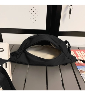 Detail view of the black canvas fanny pack showing zip closure and textured fabric