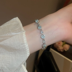 Detailed view of an elegant silver bracelet featuring light blue heart-shaped zircons