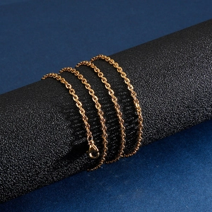 Detail of a polished gold-plated stainless steel cross chain with a lobster clasp closure