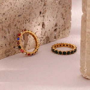 Detail of gold-plated rings with multi-color and emerald zircons on textured stone