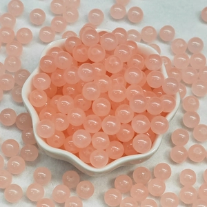 Perles en verre rose translucide dans un bol blanc pour la création de bijoux