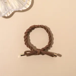 Close-up of dark brown braided hair tie with elegant gold metal tips and bow knot