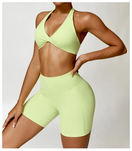 Detail of neon green sports bra with twist front and high waist compression shorts