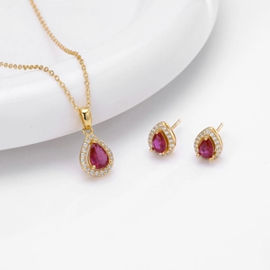 Detailed shot of gold jewelry set featuring red pear-cut stones and white zircon accents