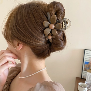 Pinza per capelli a fiore marrone in resina acrilica su lunghi capelli scuri vista dietro