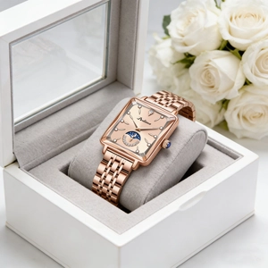 Elegant square rose gold watch with moon phase dial on a grey cushion with white roses