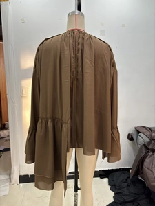 Detail shot of brown chiffon top showing ruffles and pleated sleeve design on a mannequin