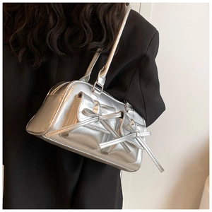 Détail du sac à bandoulière argenté métallisé avec nœud sur un mannequin en blazer noir