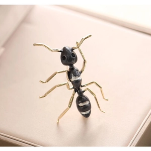 Detailed view of striped enamel ant brooch in gold and black on jewelry box