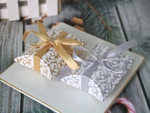 Close-up of patterned pillow gift boxes with gold and silver ribbons for wedding favors