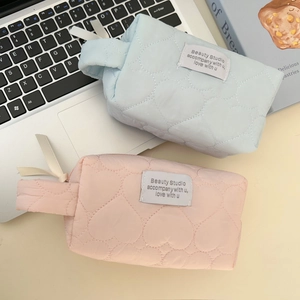 Close-up of heart-quilted travel makeup bags in pink and blue with a zipper handle