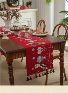 Detailed close-up of red Christmas table runner with festive prints and tassel fringe