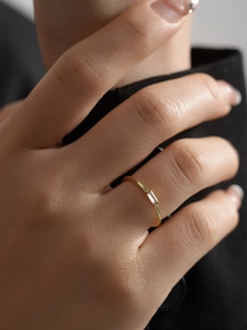 Close-up of gold beaded ring featuring a rectangular zircon on a finger