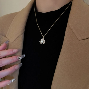 Gros plan d'un collier doré avec pendentif perle et halo de zircons sur mannequin