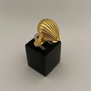 Gouden titaniumstalen ring met gedetailleerd schelpontwerp op een zwarte sokkel