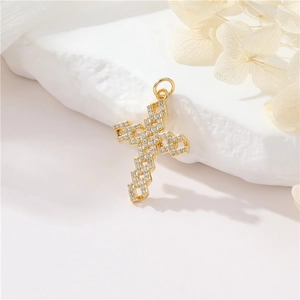 Macro detail of a 14K gold-plated cross pendant with inlaid zircons on a stone base