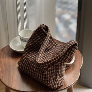 Detail of vintage brown plaid wool fabric texture on a small shoulder bag with soft natural light