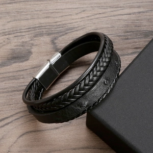 Close-up of black braided leather bracelet with silver magnetic clasp on a wooden background