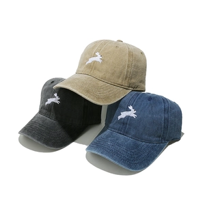 Close-up of three washed cotton baseball caps with embroidered rabbit logos in various colors