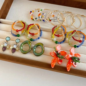 Collection of vintage glass flower earrings and beaded hoops on a velvet tray