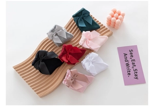 Detail of colorful bow cotton socks with ruffled edges on a wooden display tray