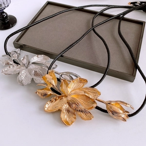 Detail of tulip flower charms in gold and silver finish on black cords with matte texture