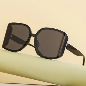 Classic black oversized sunglasses with resin lenses on a minimal studio pedestal