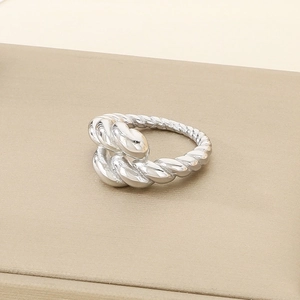 Macro shot of silver croissant ring with twisted rope design on a textured display base