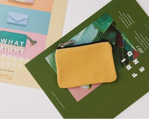 Detail of yellow canvas coin purse with black zipper and silver hardware on a desk