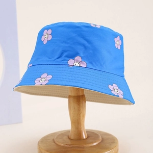 Detail of kids blue bucket hat with purple smiling flower print on a wooden stand