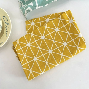 Détail de set de table en toile jaune avec motifs géométriques blancs et assiette
