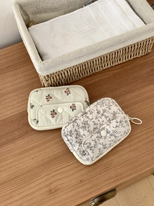 Quilted cotton multi-functional pouches in floral patterns with snap closure on wood