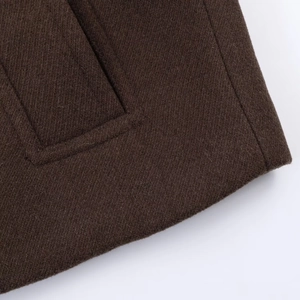 Detail of dark brown wool coat showing diagonal twill texture and premium stitching