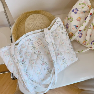 Detailed texture of quilted cotton floral tote bag with embroidered fabric label detail