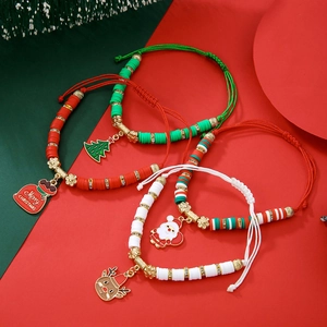 Détail de bracelets de Noël avec breloques Père Noël et flocons sur fond rouge et vert