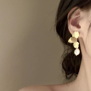 Detail of matte gold petal earrings with white baroque freshwater pearls on model