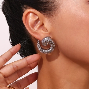 Macro close-up of a silver stainless steel spiral earring worn on a model ear