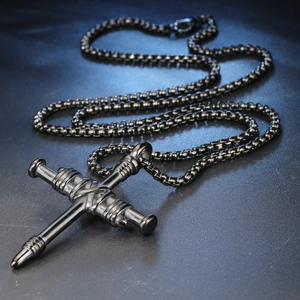 Gros plan d'un pendentif croix en acier titane noir avec chaîne en métal style punk
